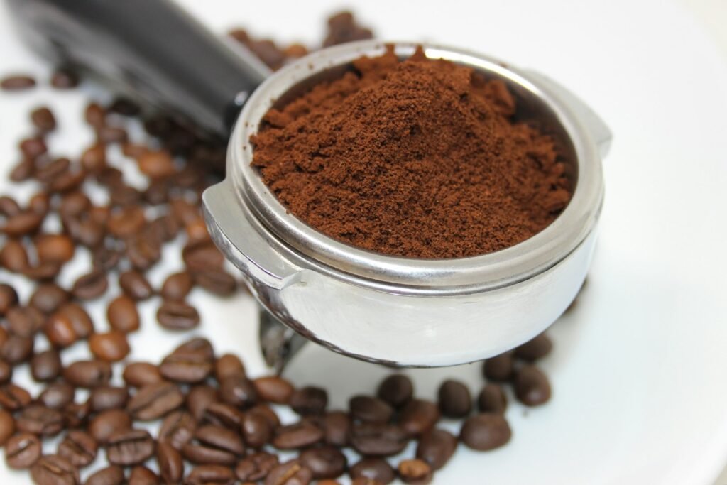 Portafilter basket heaped with ground coffee, the kind of dose a dosing funnel keeps from spilling