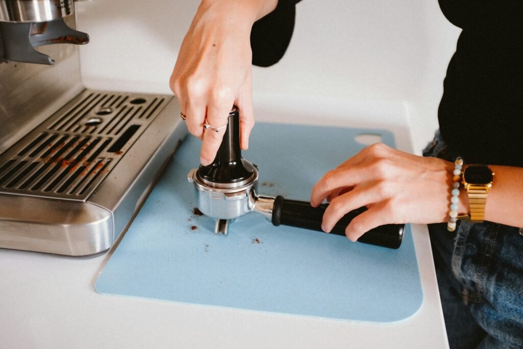 Barista tamping espresso grounds in a portafilter on a silicone tamping mat
